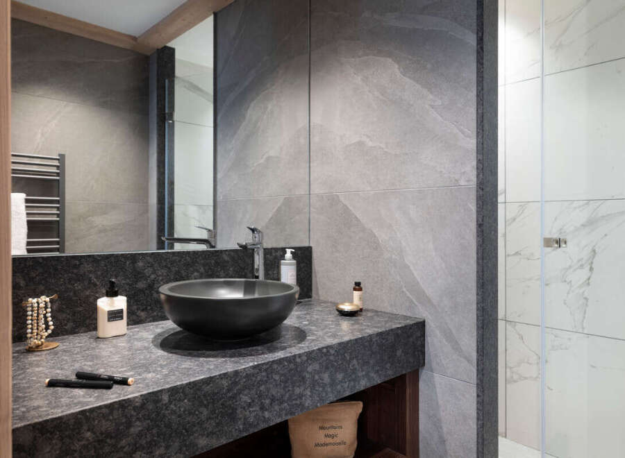 This luxurious bathroom boasts a sleek, modern design with dark granite countertops and a stylish black sink.