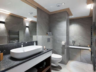 This luxurious bathroom boasts a modern design with sleek gray tiles, a spacious vanity with granite countertop, and a contemporary oval sink.