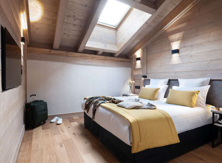 This stunning bedroom boasts a cozy wooden interior with a vaulted ceiling and skylights, creating a bright and airy atmosphere.