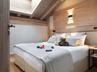 Cozy chalet bedroom with a double bed, plush bedding, and wooden accents.