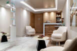 Relax in our luxurious spa waiting area, featuring plush armchairs, modern artwork, and a sleek reception desk.