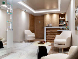 Relax in our luxurious spa waiting area, featuring plush armchairs, modern artwork, and a sleek reception desk.