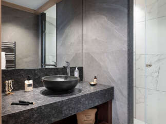 This luxurious bathroom boasts a sleek, modern design with dark granite countertops and a stylish black sink.