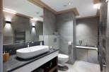 This luxurious bathroom boasts a modern design with sleek gray tiles, a spacious vanity with granite countertop, and a contemporary oval sink.