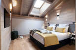 This stunning bedroom boasts a cozy wooden interior with a vaulted ceiling and skylights, creating a bright and airy atmosphere.