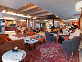 The hotel lobby boasts a stunning design with a blend of modern and traditional elements, featuring a cozy fireplace as a centerpiece.