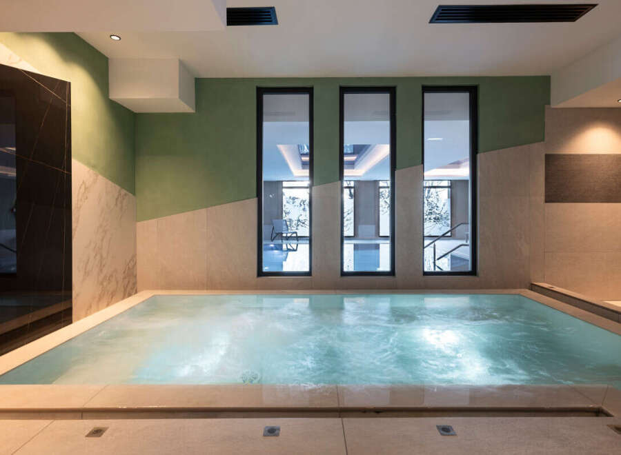 Indulge in tranquility at our luxurious spa, featuring a soothing jacuzzi with views of a serene indoor pool.