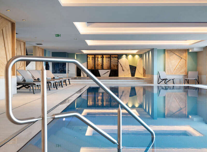 Indulge in the serene atmosphere of our indoor pool, featuring a sleek, modern design and calming color palette.