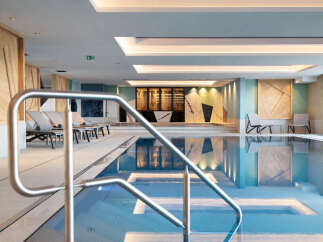 Indulge in the serene atmosphere of our indoor pool, featuring a sleek, modern design and calming color palette.