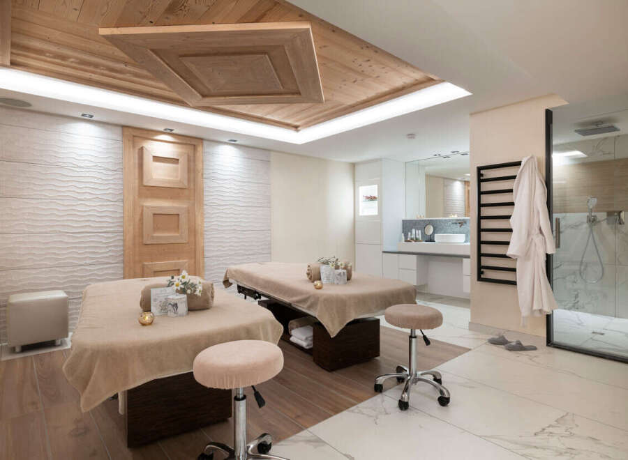 Indulge in tranquility at our luxurious spa, featuring two plush massage tables draped in soft beige linens, complete with plush stools for ultimate comfort.
