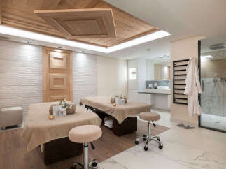 Indulge in tranquility at our luxurious spa, featuring two plush massage tables draped in soft beige linens, complete with plush stools for ultimate comfort.