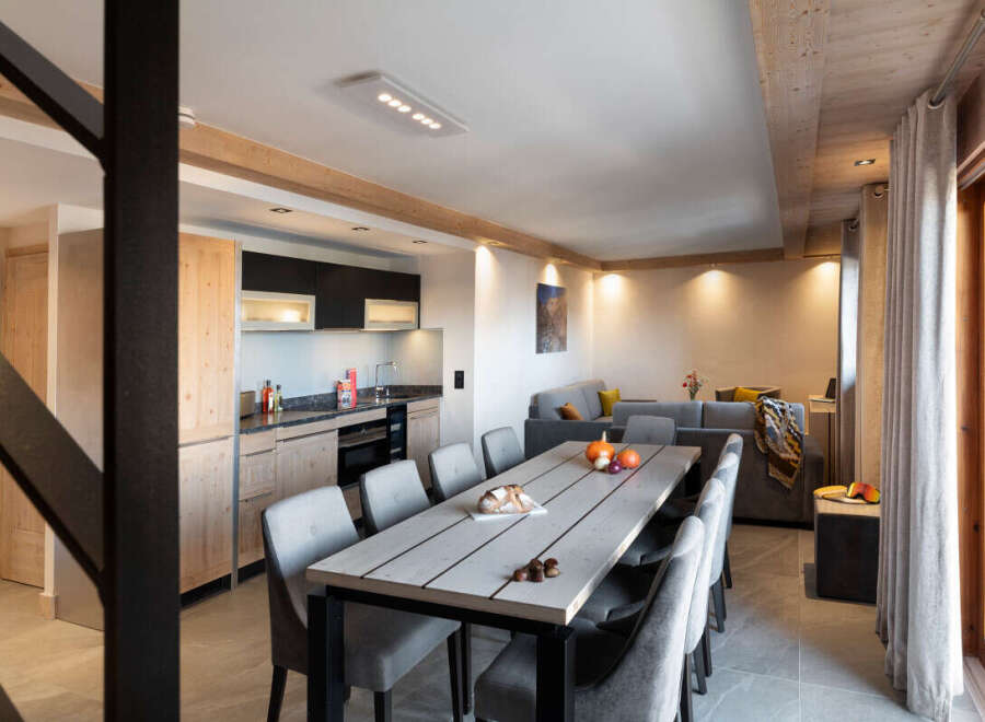 This stunning apartment boasts a spacious open-plan living area with a large dining table perfect for gatherings, a fully equipped modern kitchen, and a cozy living room with comfortable seating.
