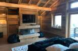 This stunning chalet boasts a rustic-chic bedroom with exposed wooden beams, a cozy fireplace, and plush furnishings.