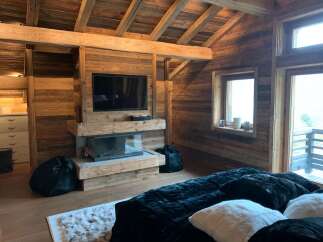 This stunning chalet boasts a rustic-chic bedroom with exposed wooden beams, a cozy fireplace, and plush furnishings.