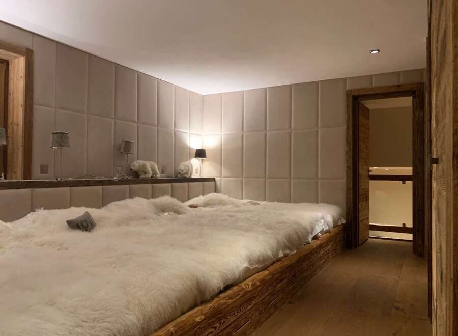 Luxurious chalet bedroom with plush sheepskin bedding and rustic wooden platform bed.
