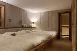 Luxurious chalet bedroom with plush sheepskin bedding and rustic wooden platform bed.