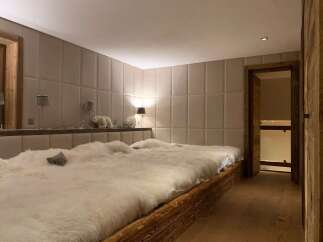 Luxurious chalet bedroom with plush sheepskin bedding and rustic wooden platform bed.