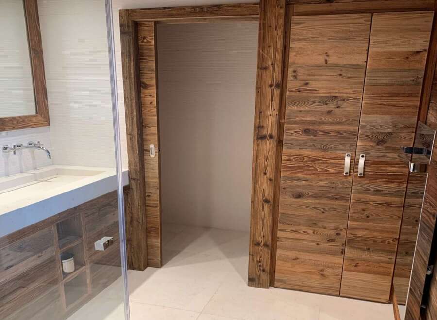 Luxury bathroom boasts a stunning reclaimed wood vanity and double doors, offering ample storage.