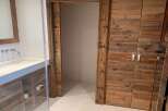 Luxury bathroom boasts a stunning reclaimed wood vanity and double doors, offering ample storage.