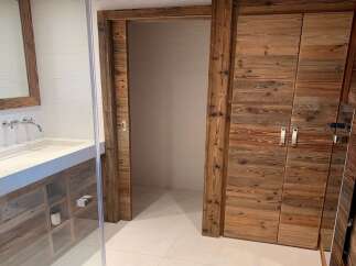 Luxury bathroom boasts a stunning reclaimed wood vanity and double doors, offering ample storage.