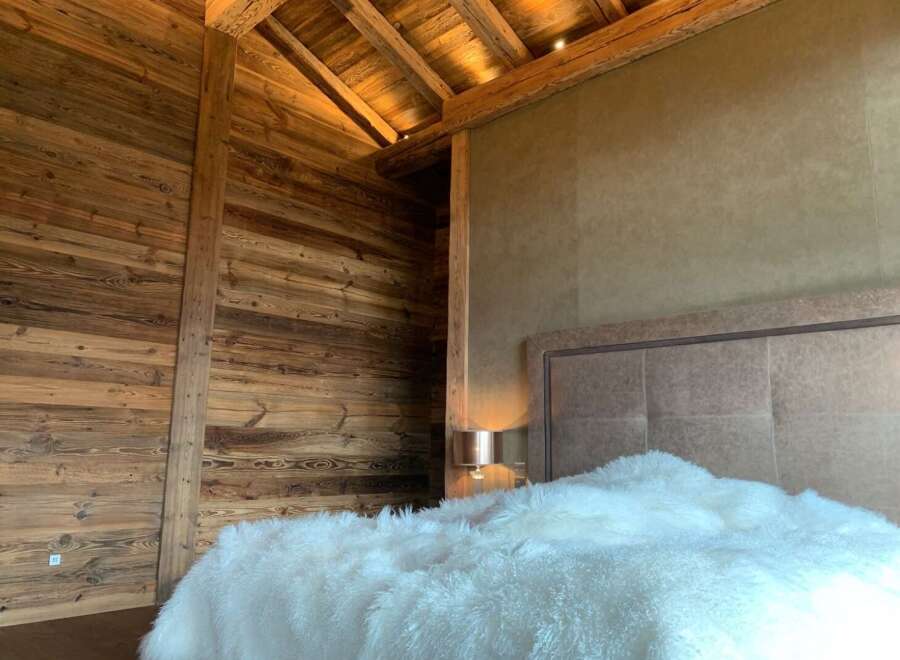 Luxurious chalet bedroom with rustic wood walls and beamed ceiling.