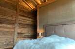 Luxurious chalet bedroom with rustic wood walls and beamed ceiling.