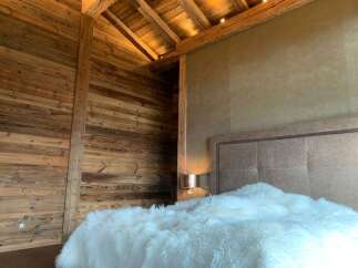 Luxurious chalet bedroom with rustic wood walls and beamed ceiling.