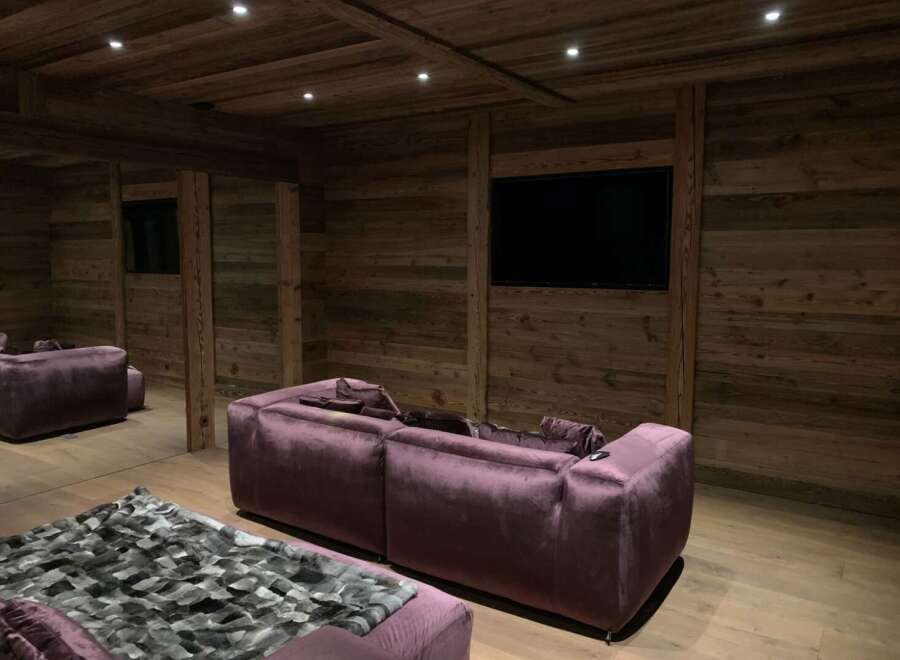 Luxurious chalet home theater with stunning reclaimed wood walls and plush velvet seating.