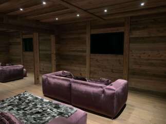 Luxurious chalet home theater with stunning reclaimed wood walls and plush velvet seating.