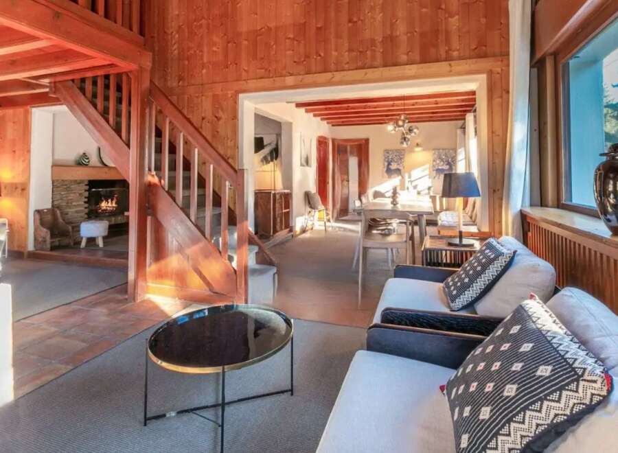 Cozy chalet with wooden interior, featuring a fireplace, open living area, and stunning mountain views.