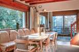 This stunning chalet boasts a spacious dining area with a large table perfect for family gatherings, bathed in natural light from expansive windows showcasing breathtaking views.
