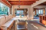 This stunning chalet boasts a spacious dining area with a long wooden table perfect for gatherings, complemented by comfortable built-in seating with sheepskin throws.