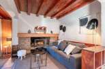 Cozy living room with a stone fireplace, wooden beams, and comfortable gray sofa.