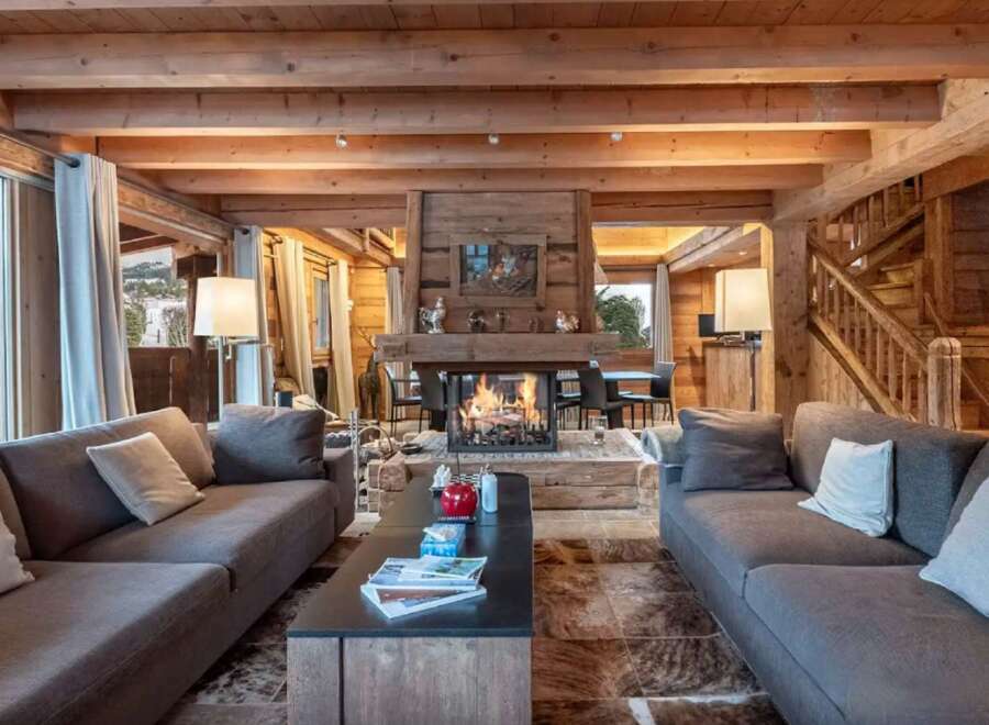 This stunning chalet boasts a spacious living area with a cozy fireplace, perfect for relaxing after a day on the slopes.