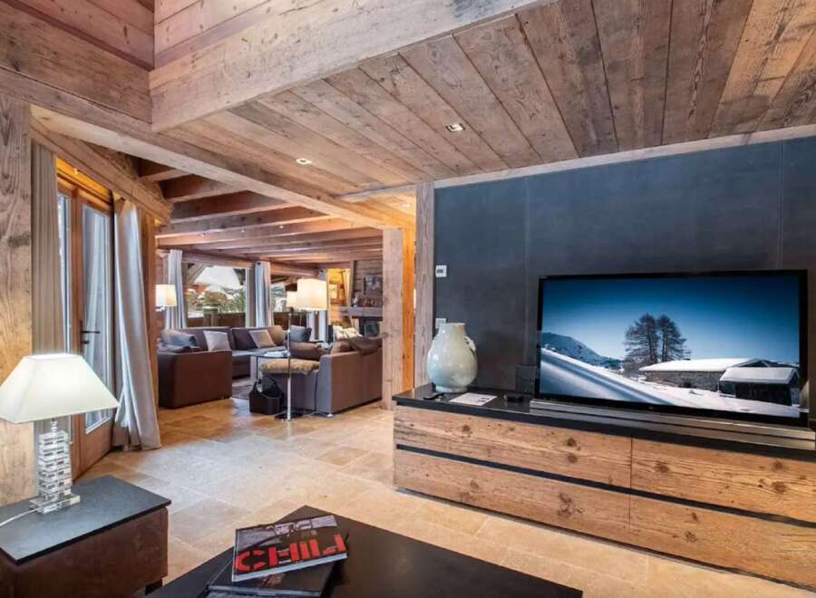 This stunning chalet boasts a spacious open-plan living area with exposed wooden beams and a cozy fireplace.