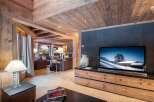 This stunning chalet boasts a spacious open-plan living area with exposed wooden beams and a cozy fireplace.