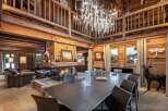 This luxurious chalet boasts a stunning open-plan living area with a large dining table perfect for gatherings, a cozy fireplace, and high ceilings.