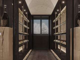 This luxurious wine cellar boasts a lime ceiling, glass door, and wide-slat parquet flooring.