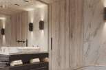 Luxurious master bathroom boasts marble bathtub, wide stone basin, and dark wood cabinetry.