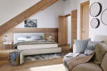 This stunning bedroom boasts a cozy and modern design, featuring a plush bed, wooden floors, and a stylish seating area.