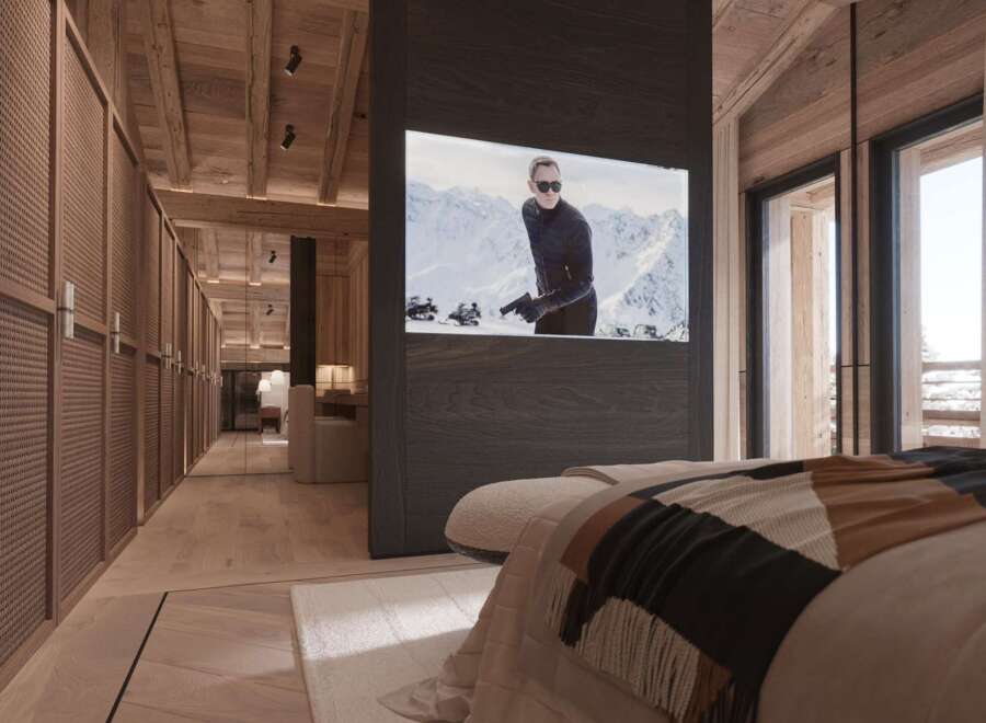 Luxury chalet bedroom with stunning mountain views and a built-in TV showcasing a James Bond movie.