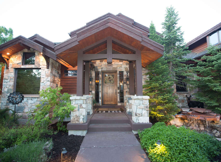 This stunning home boasts a beautiful stone facade and a welcoming wooden front door.