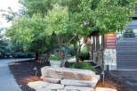 This stunning property boasts a beautifully landscaped front yard, featuring a natural stone pathway leading to a unique rock bench.