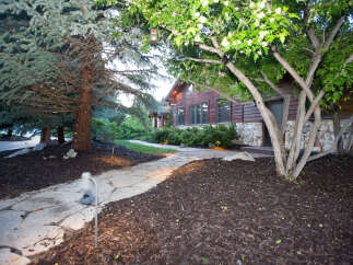 Discover the charm of this stunning property, featuring a beautifully landscaped pathway leading to a rustic wooden home.