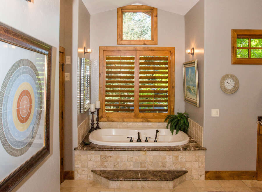 This luxurious bathroom features a stunning soaking tub surrounded by elegant tile work and a marble countertop.