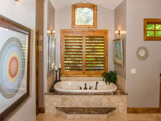 This luxurious bathroom features a stunning soaking tub surrounded by elegant tile work and a marble countertop.