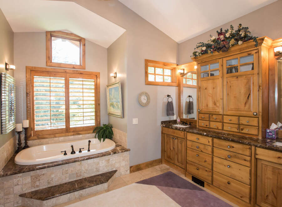 Step into luxury with this stunning bathroom featuring a beautiful soaking tub and elegant cabinetry.