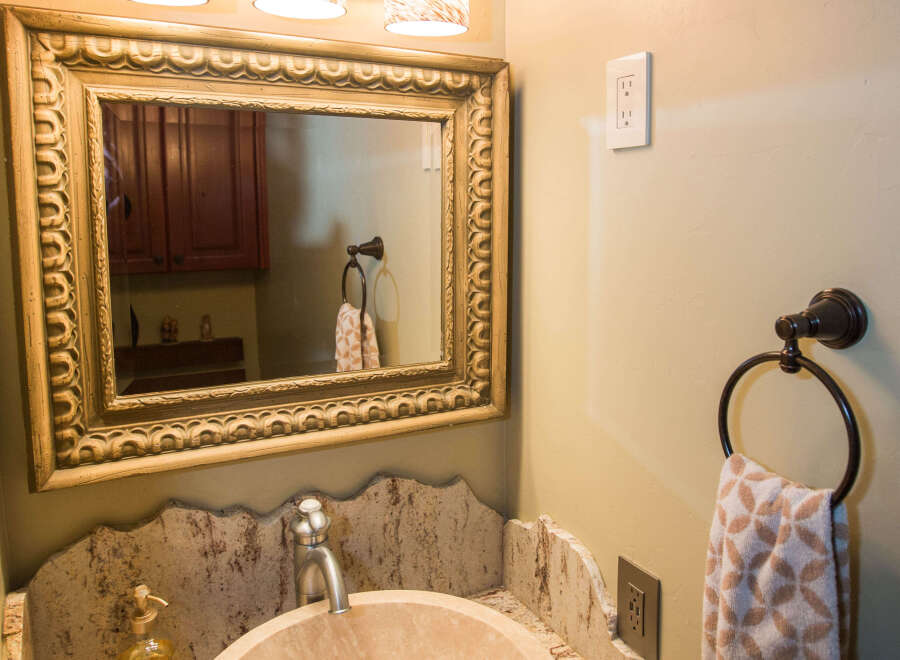This elegant bathroom features a unique stone sink and a beautifully framed mirror.