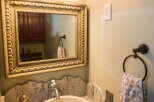 This elegant bathroom features a unique stone sink and a beautifully framed mirror.