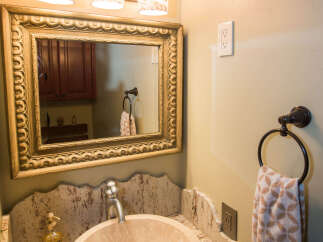 This elegant bathroom features a unique stone sink and a beautifully framed mirror.